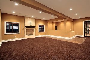A dark carpet covering the entire floor of a spacious house, with beige walls, white flooring, and accents.