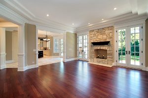 A spacious house with dark wooden floors, walls in beige/green tones, and white accents.