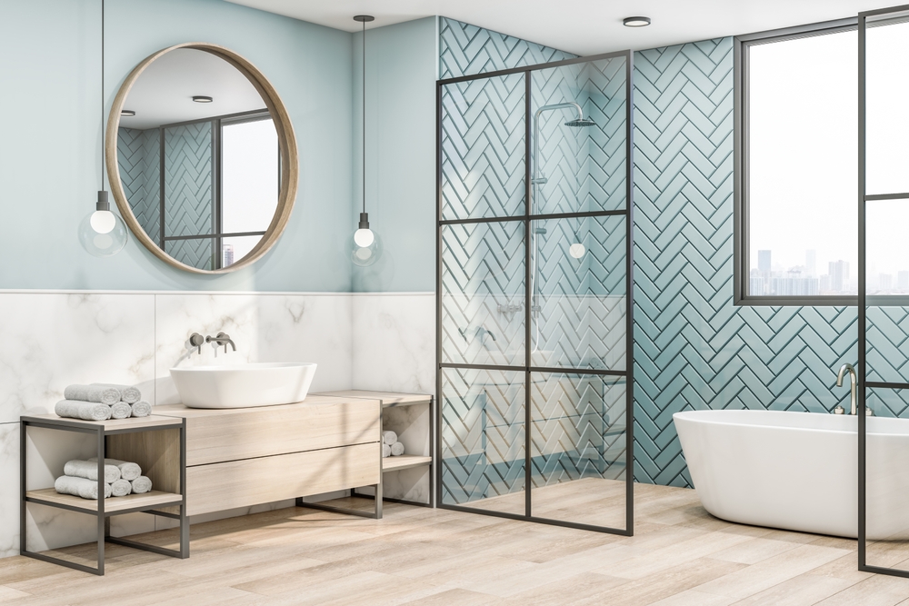 Side view on eco interior design of bathroom with wooden frame of round mirror on blue wall, wooden sink cabinet and floor